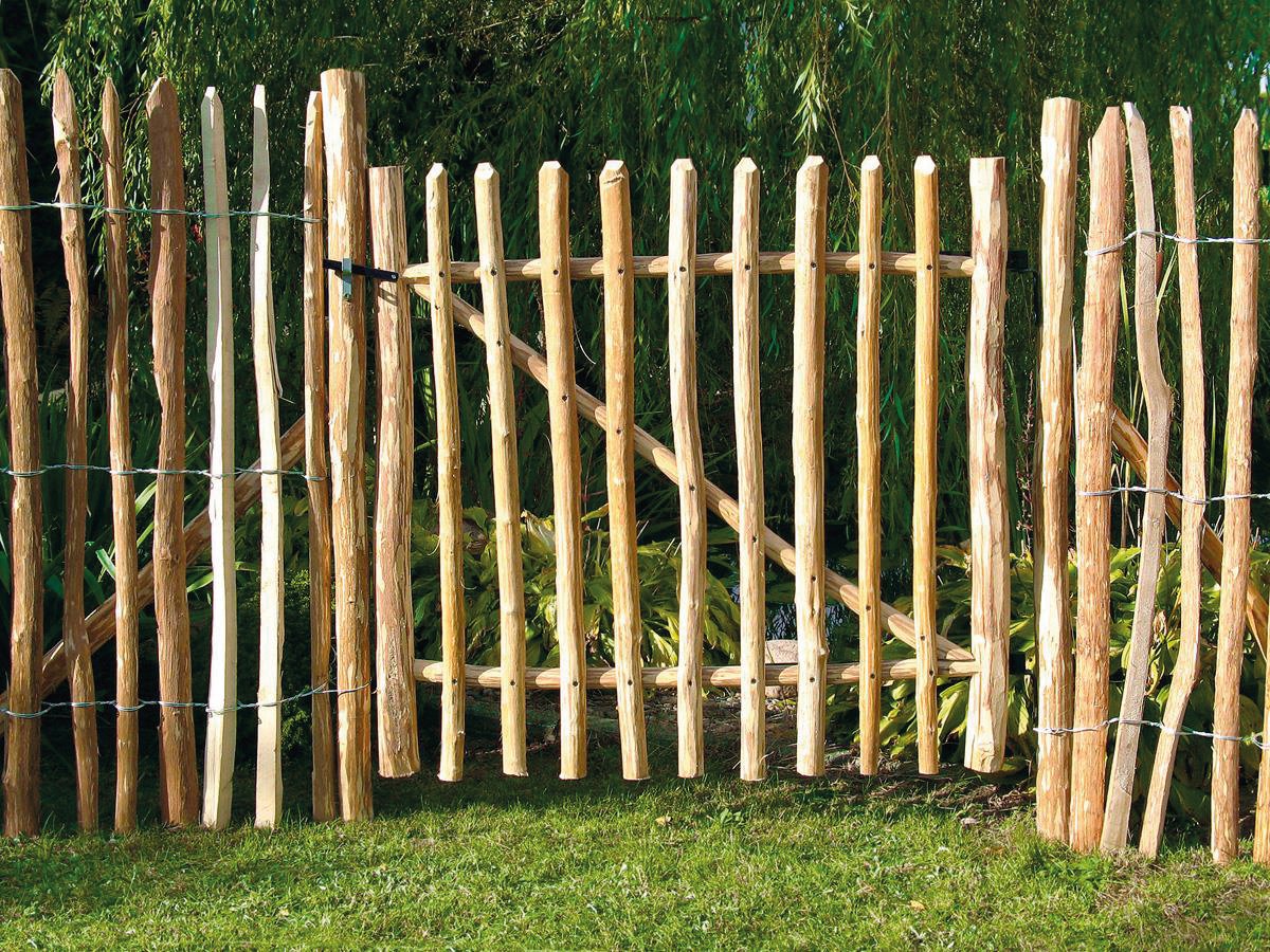 Haselnuss Vorgartenzauntor, 100 cm breit, naturbelassen; gefertigt aus vertikalen, unbehandelten Haselnussstäben mit unregelmäßiger Form, eingefasst von passendem Zaun, auf Rasenfläche im Garten stehend
