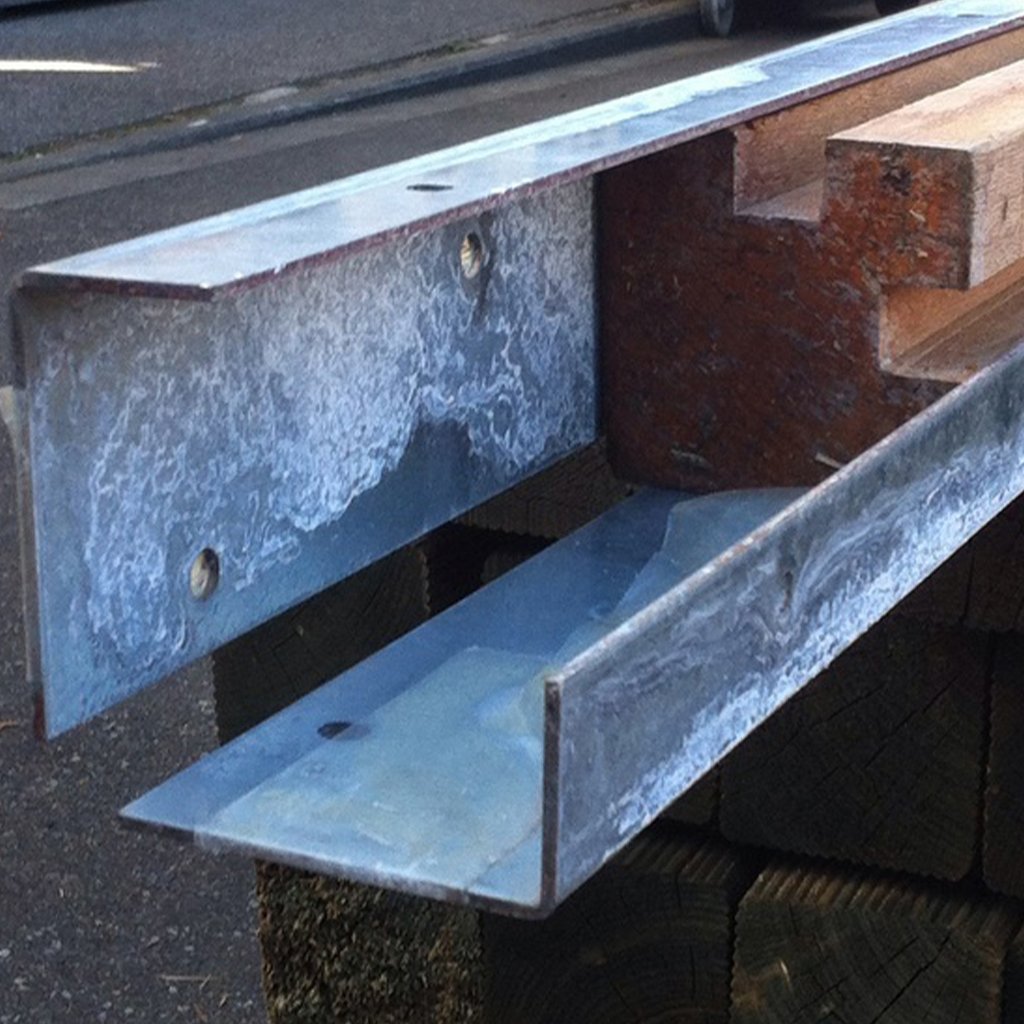 Winkelanker aus Metall zum Einbetonieren, Maße 550 x 80 x 40 mm, Ansicht von nah mit sichtbaren Befestigungslöchern und Holzleiste, im Außenbereich aufgeständert